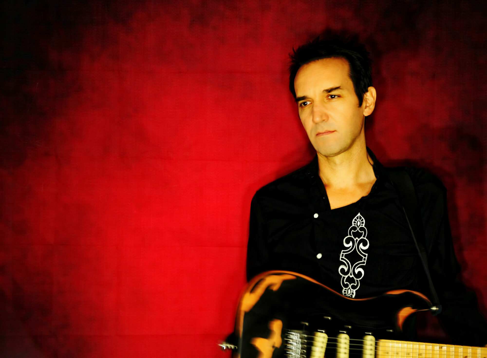 louis l'insolence à la guitare fond rouge